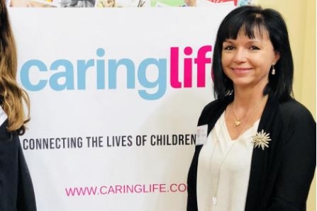 a woman standing in front of a banner that reads caring life 