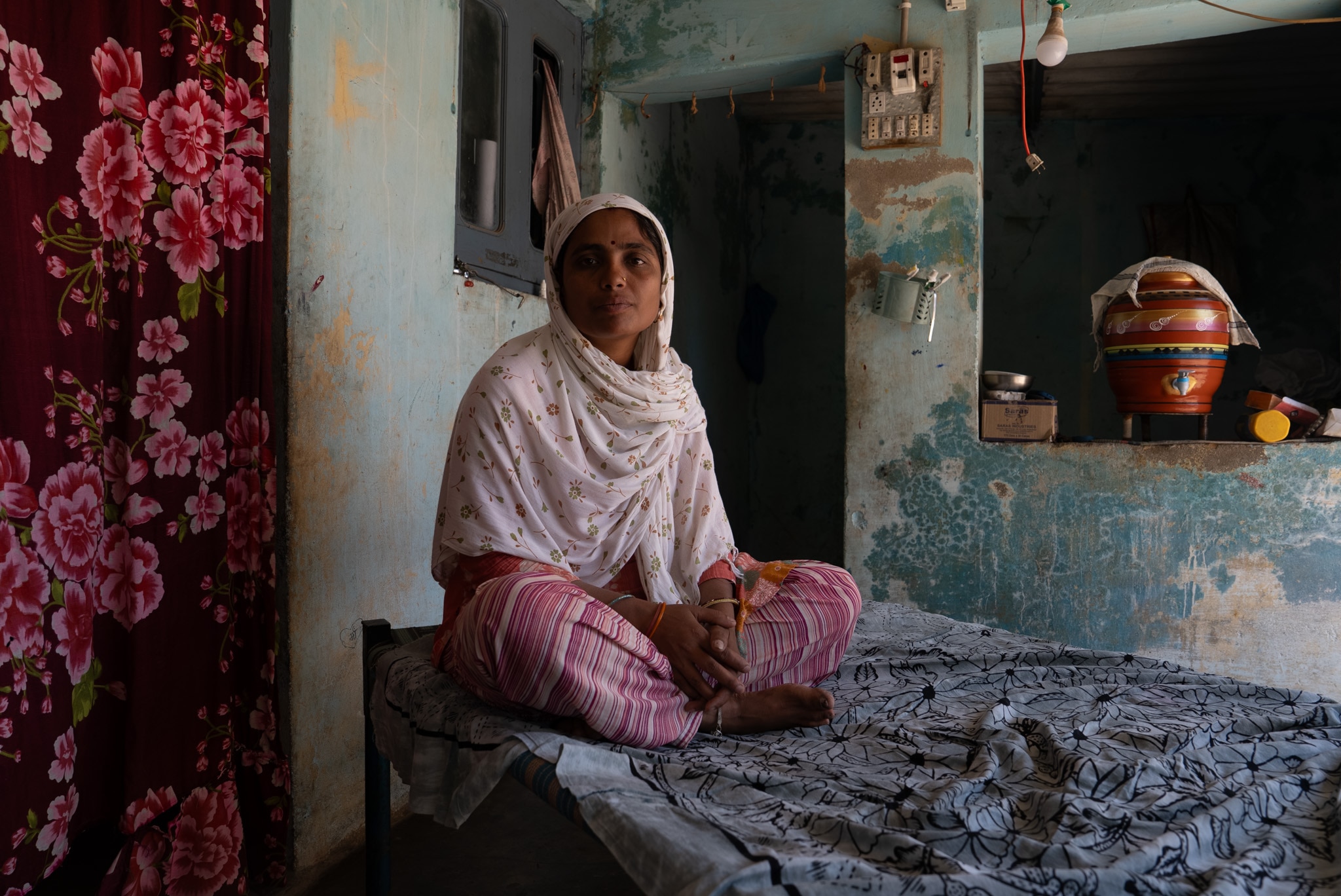 An Indian woman sits cross legged on the ground.