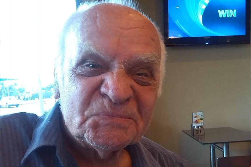 A portrait of a man sitting in a cafe wearing a blue shirt.