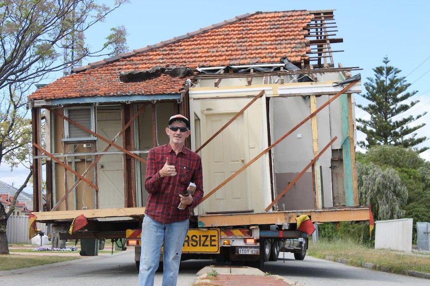 Howie Johnstone stands in front of a demountable house on a truck trailer.
