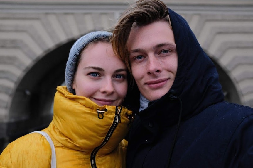 A young couple rugged up in thick coats smiling at the camera