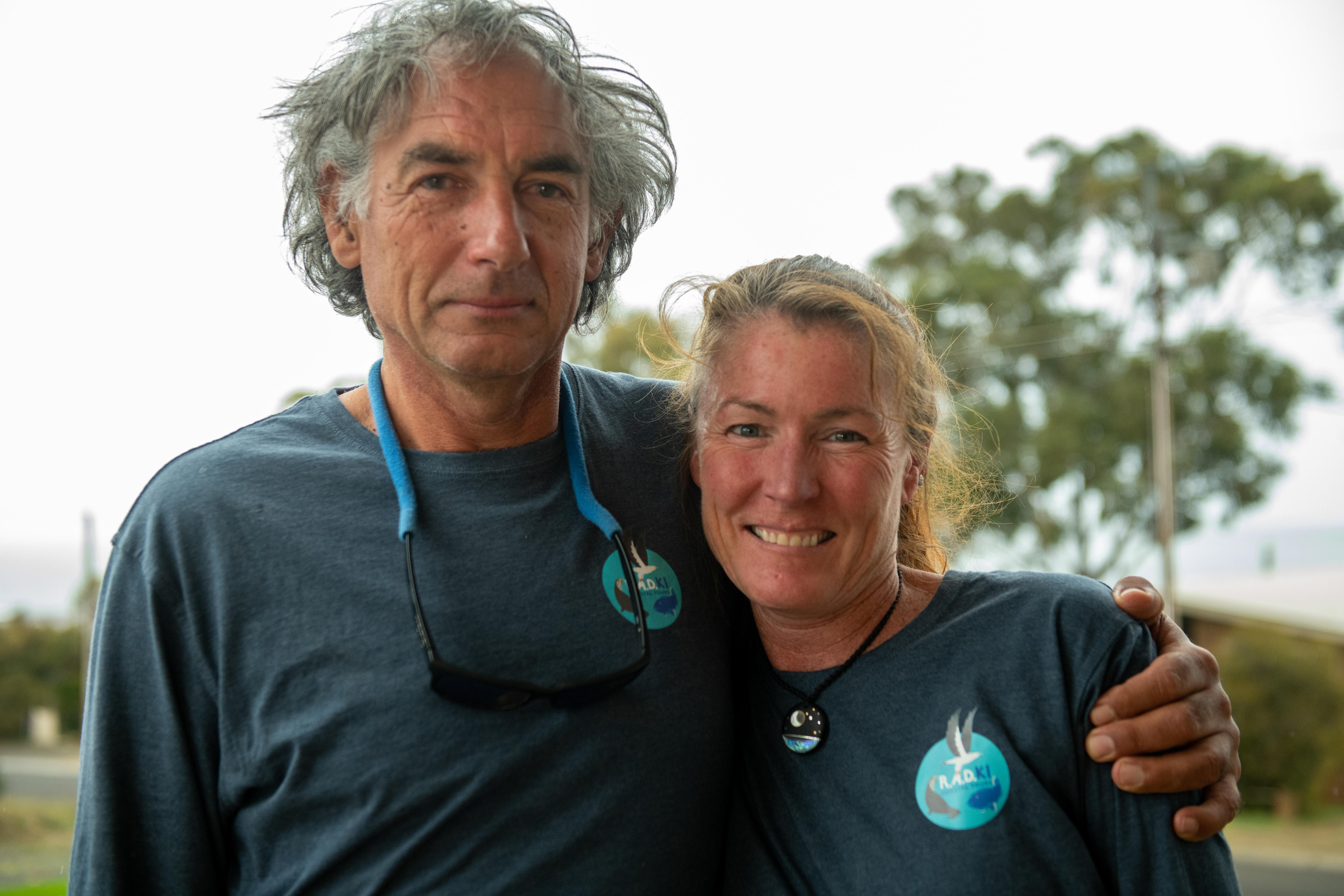 Man with arm around woman, both smiling wearing matching t-shirts.