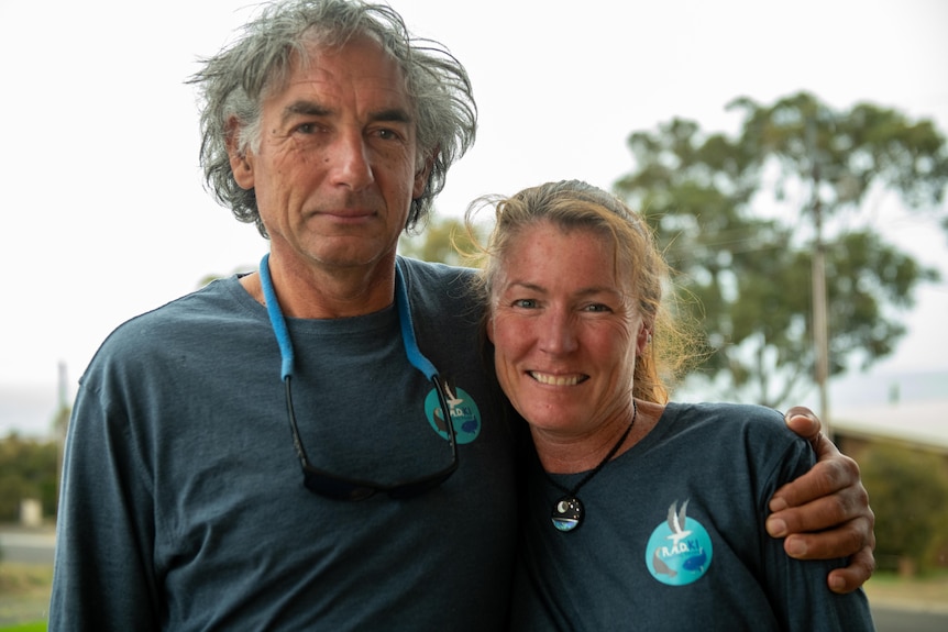 Man with arm around woman, both smiling wearing matching t-shirts.