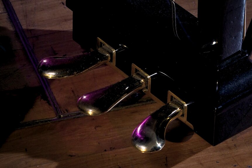 The three pedals of a grand piano.