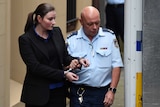 Harriet Wran being escorted to a prison transport vehicle at the NSW Supreme Court.