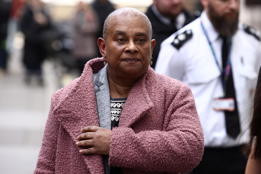 A mother of killed son, Doreen Lawrence, wearing pink coat and layers of clothing walks street to high court in London. 