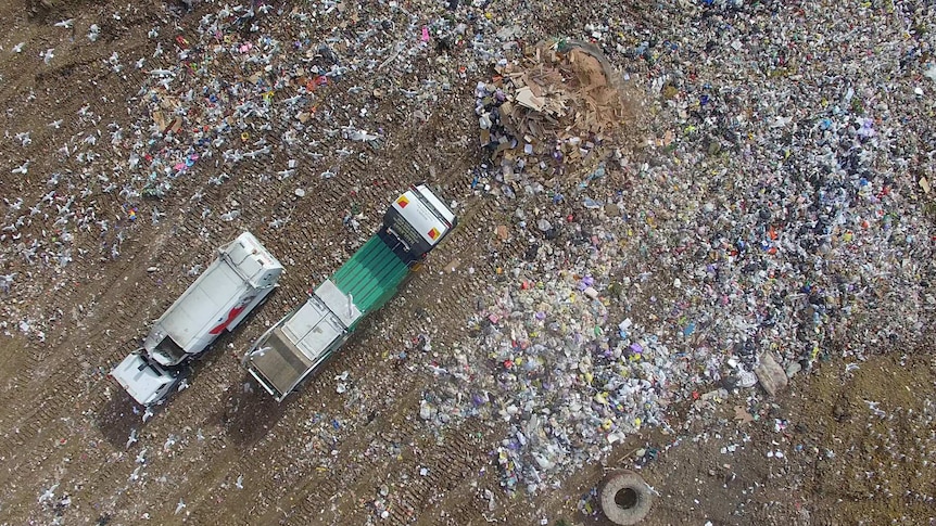 Aerial view from drone of the Werribee, Victoria tip showing piles of rubbish and two trucks.