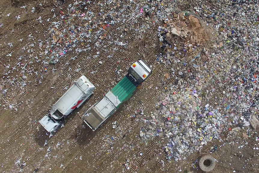 Aerial view from drone of the Werribee, Victoria tip showing piles of rubbish and two trucks.