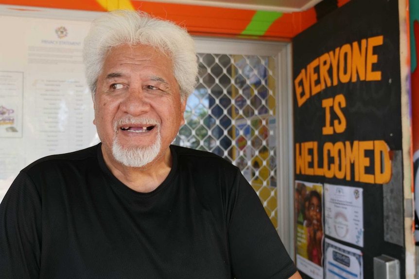 Portrait of Maori man with white hair standing on the porch of an orange building