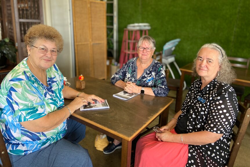 Three women sitting around a brown table inside a cafe