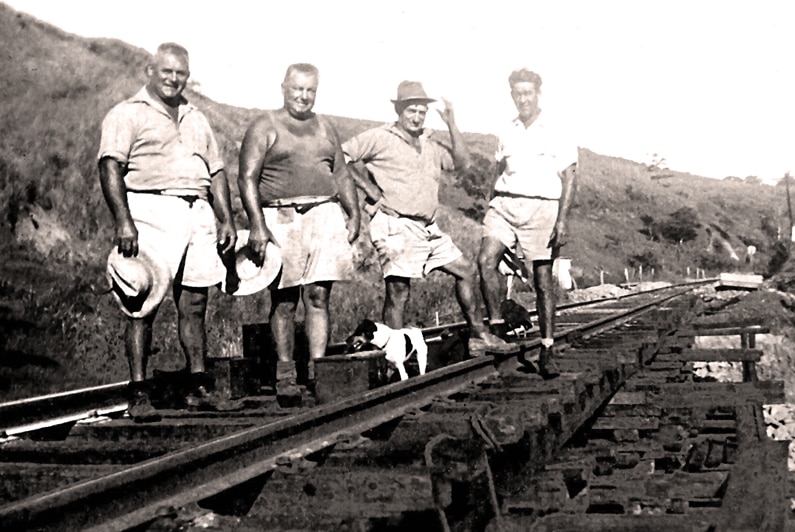 Black and white archive photo of four men and a small dog standing on an old railway line circa 1948.