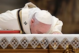 The Pope, wearing a white robe and a zuchetto kisses the altar at St Peter's.