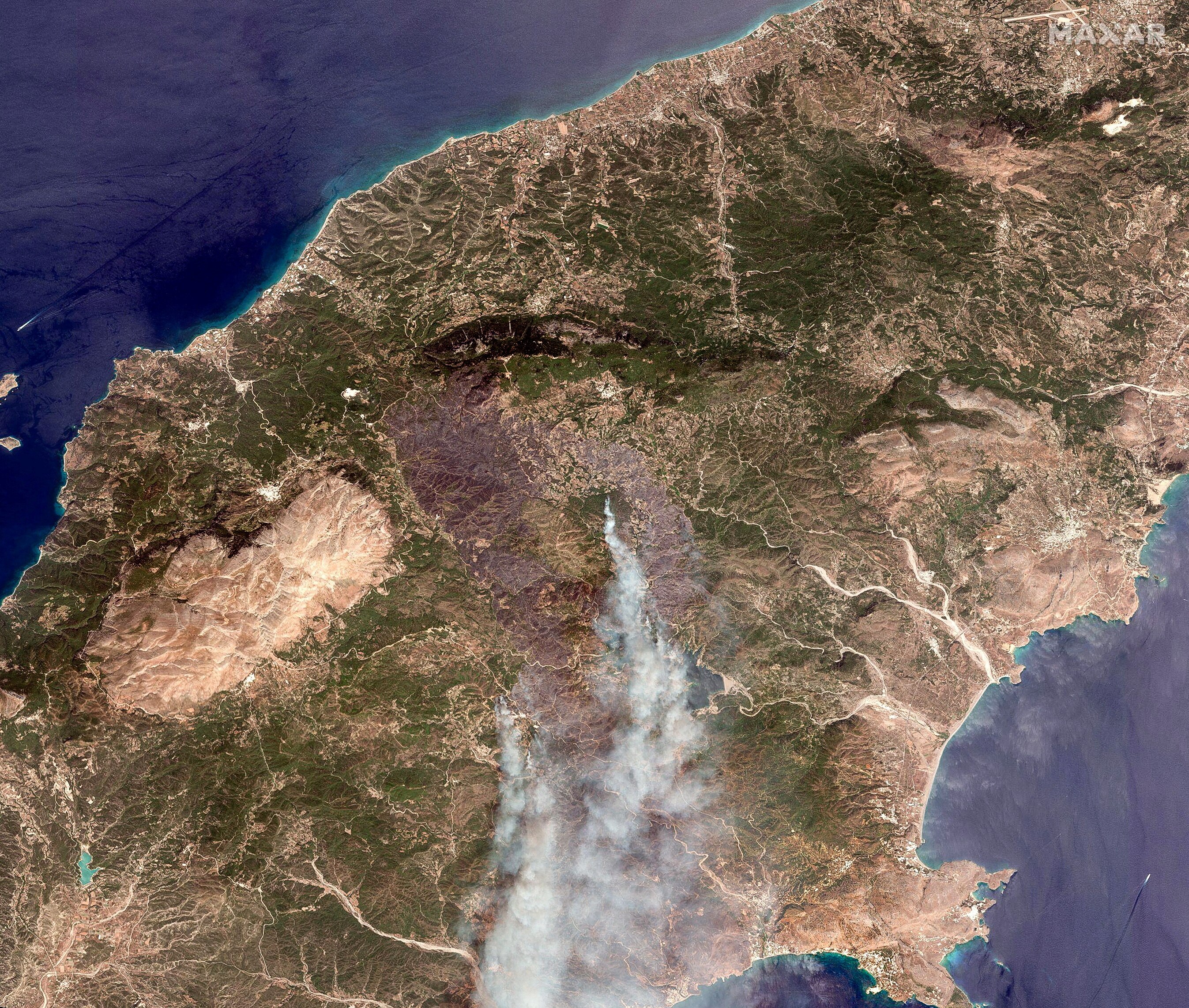 A satellite image shows smoke rising on the island of Rhodes where wildfire have been burning