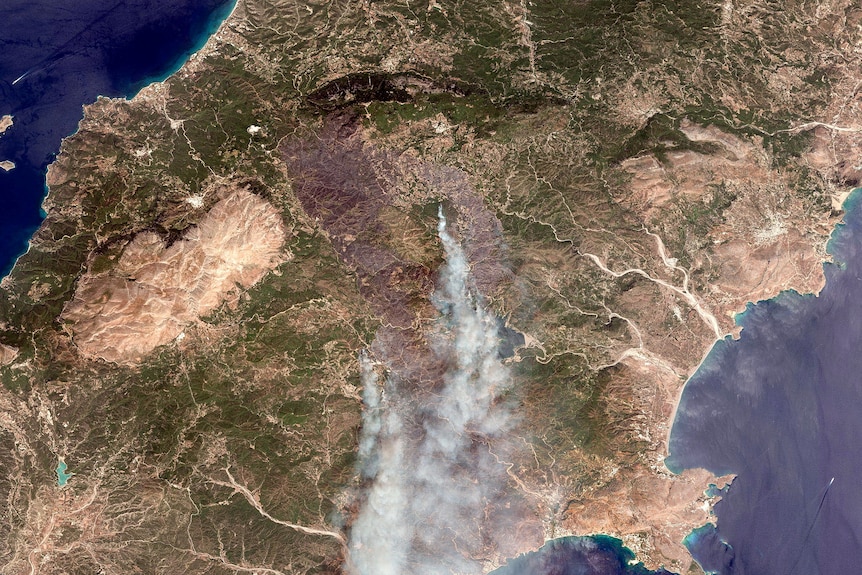 A satellite image shows smoke rising on the island of Rhodes where wildfire have been burning