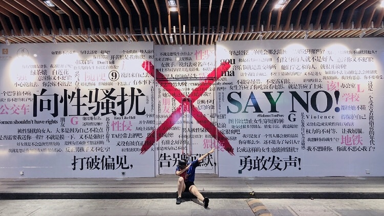 A young woman dabs in front of an anti-sexual harassment mural in Xi'an, China.