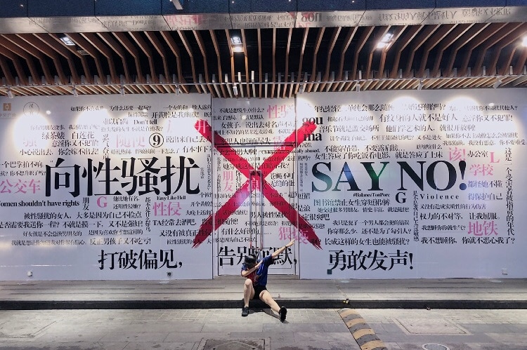 A young woman dabs in front of an anti-sexual harassment mural in Xi'an, China.