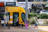 A tram passing with two people walking next to it