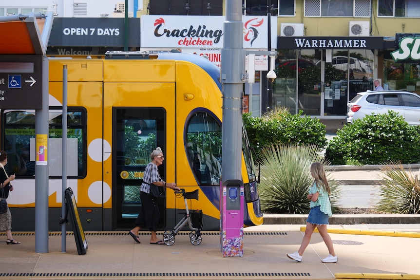 tram passing with two people walking next to it