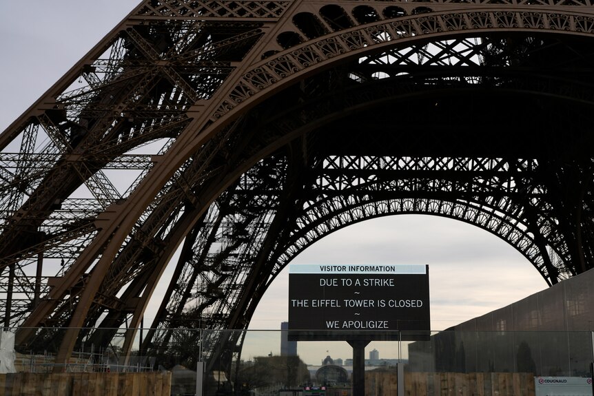 A wide shot of a sign warning of the strike in front of the Eiffel Tower.