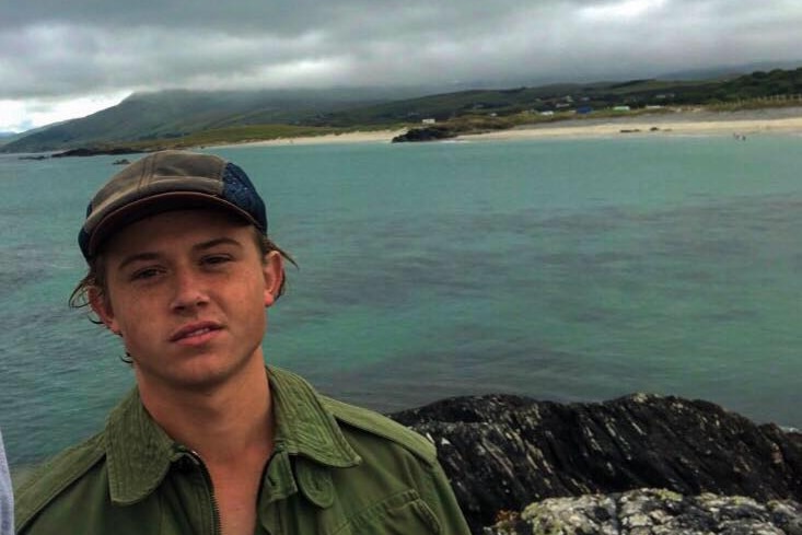 Young man on a boat with island in background.