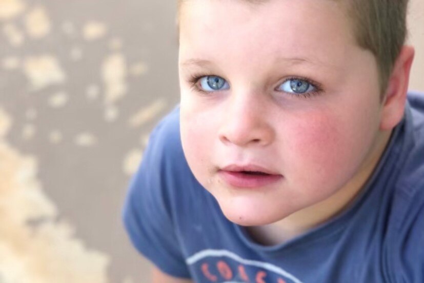 Close up of a young boy's face, he has vivid blue eyes.