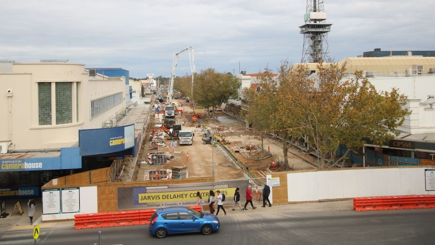 An aerial view of construction in the middle of a street full of shops