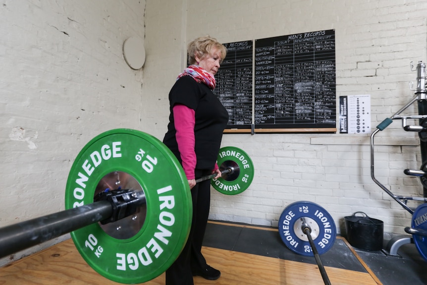 An older woman lifts 20 kilogram weights