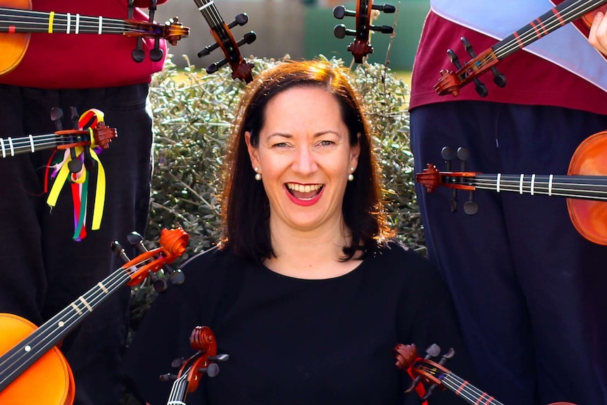Dr Anita Collins surrounded by violins
