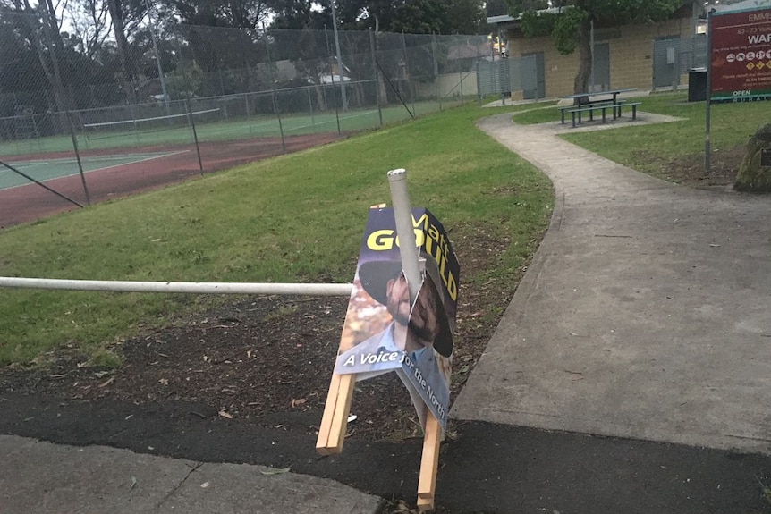 An election corflute that has been impaled on a fence.