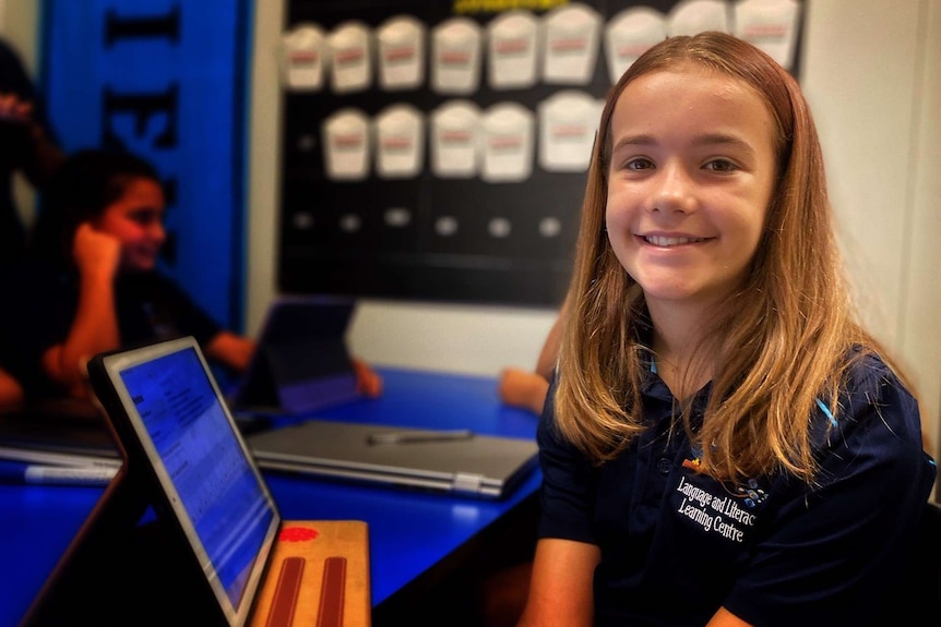 Young girls sits at desk in front of pad