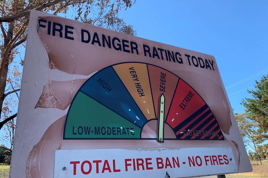 A fire danger rating sign has the arrow pointed to 'severe'. The sign has been scorched due to fire.