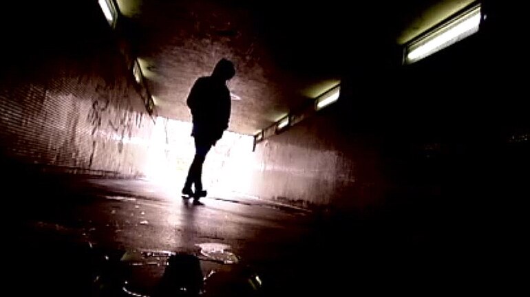 Young person silhouetted in underpass.