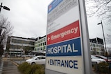 red blue and whit sign in front of a tall building and car park