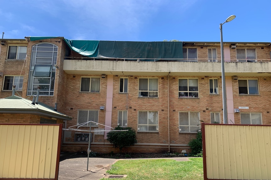 Apartment building with a green tarpaulin covering the top level.