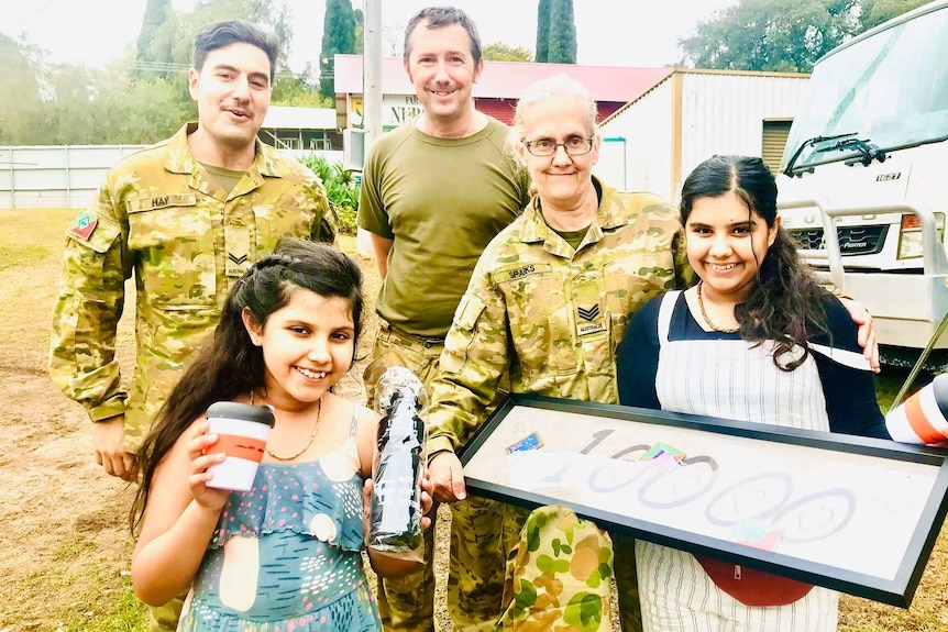 Two girls stand with Australian Army personnel