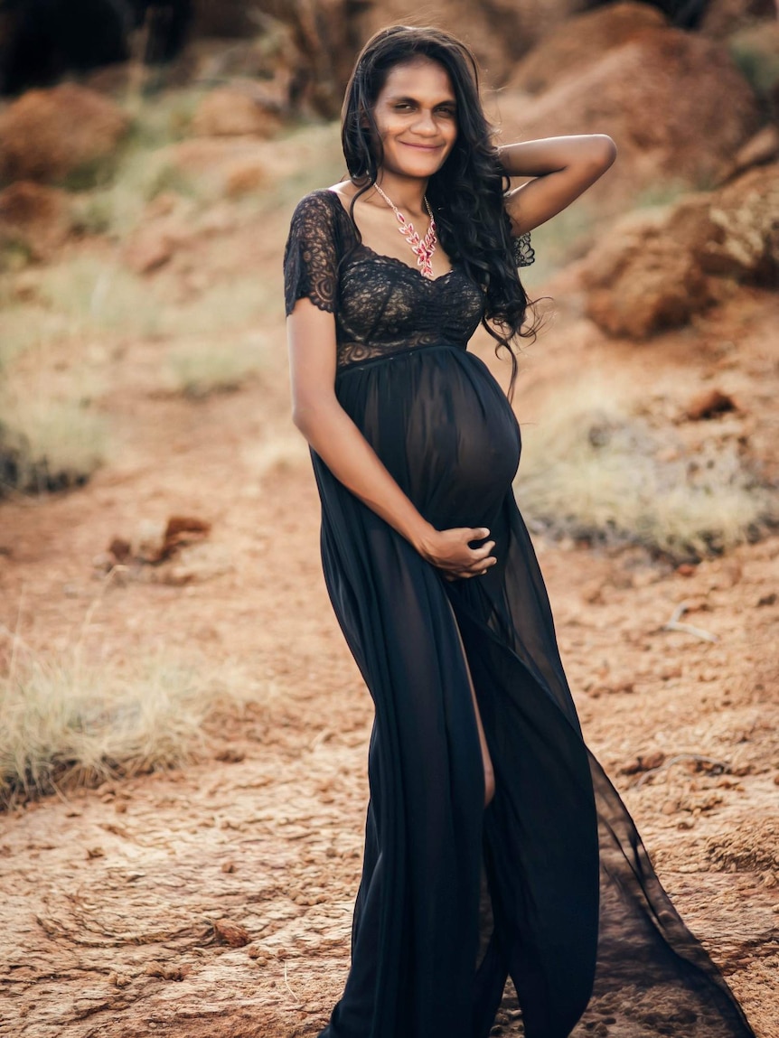 Pregnant Indigenous woman poses for a photo wearing a black flowing gown