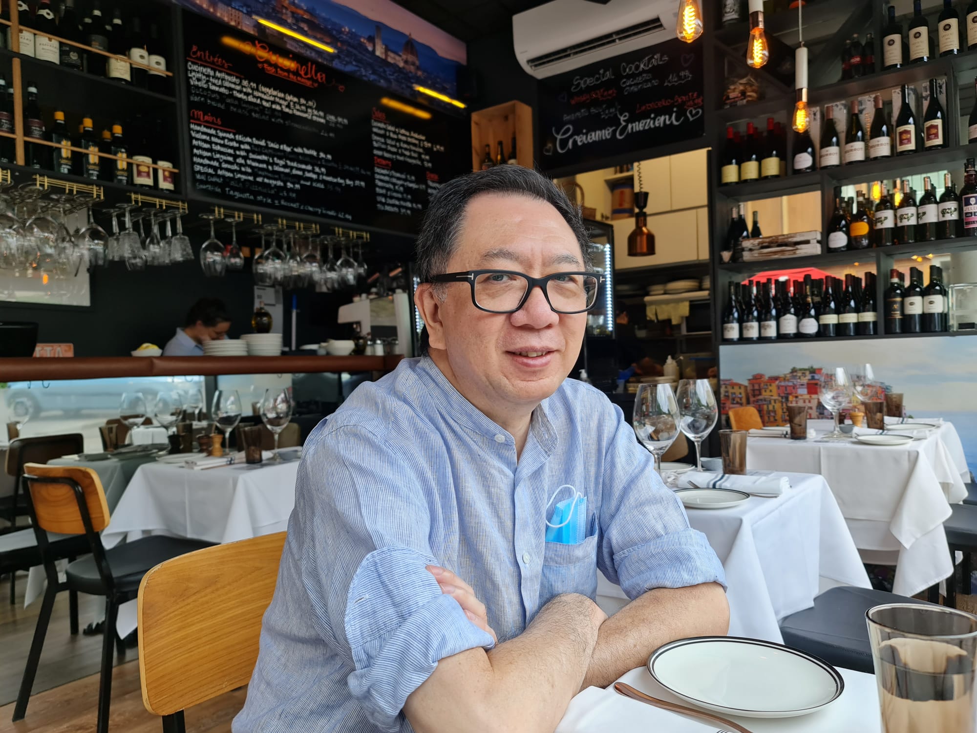 A man smiling for picture taken from his right in a restaurant.