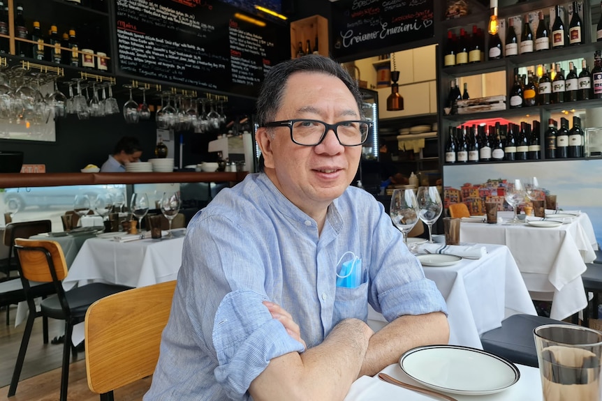 A man smiling for picture taken from his right in a restaurant.