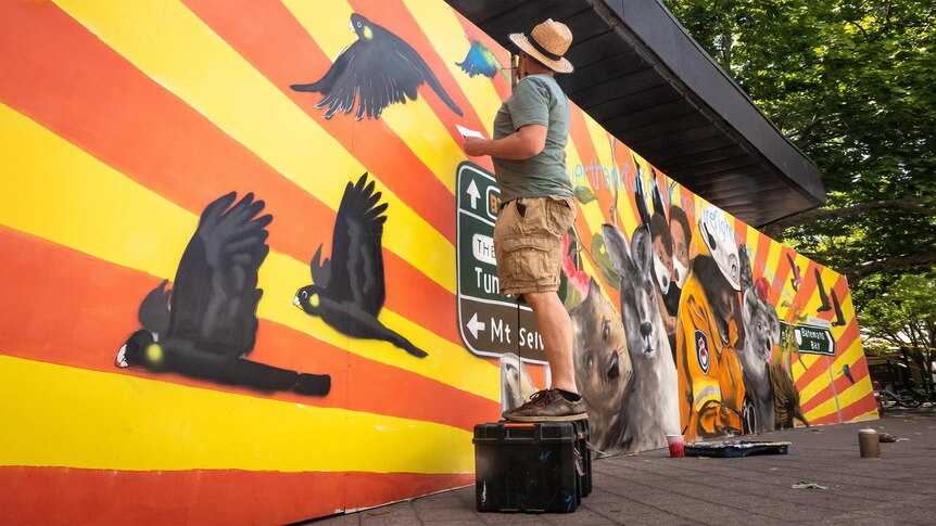 Geoff Filmer painting his bushfire tribute in Garema Place in Canberra.