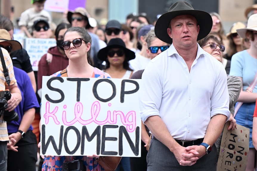 Steven Miles stands during a rally to a call for action to end violence against women.