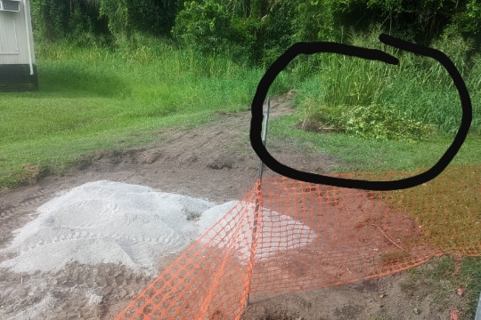 Tree lying down near dirt and sand and orange barrier at Cairns School of Distance Education