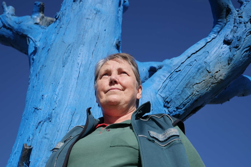 Picture of Merle Isbister in front of blue tree.
