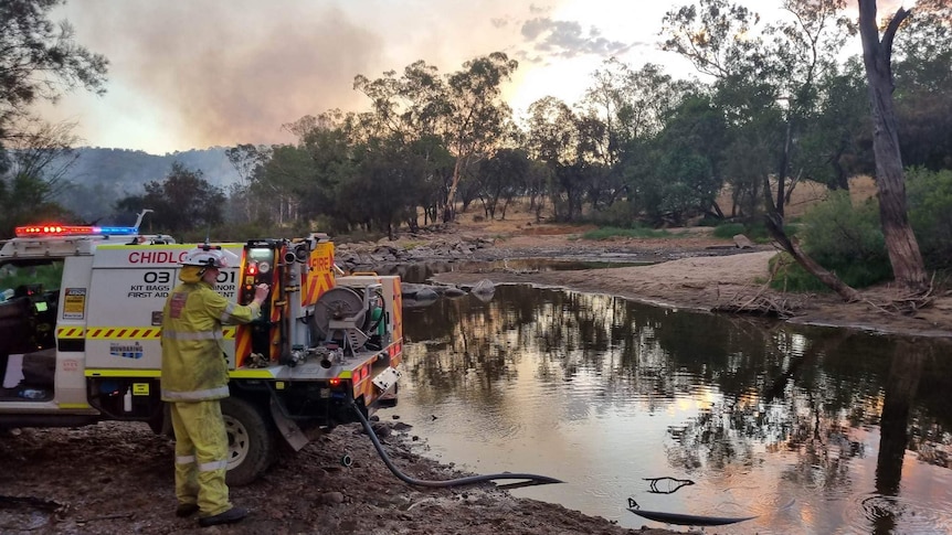 Firefighters work to control a fire near a lake