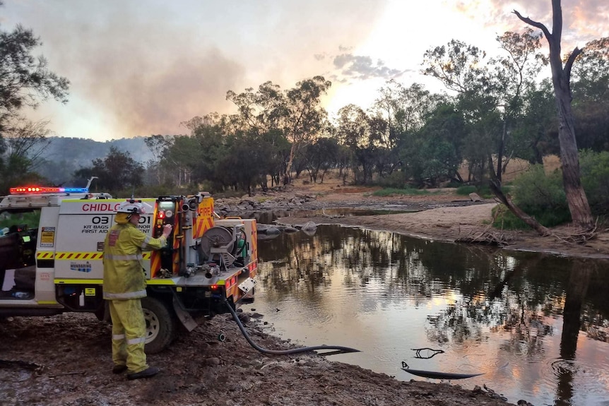 Firefighters work to control a fire near a lake