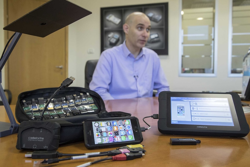 A man sits behind smartphone devices.