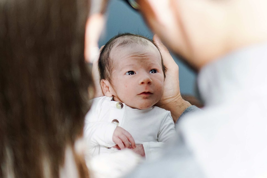 Newborn baby looking up at its parents