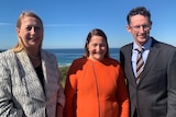 A woman stands with a man and a woman with a view of Wollongong behind.