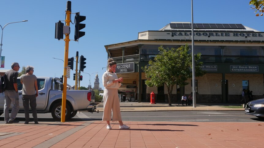 A young woman on her phone in a main street in Kalgoorlie.