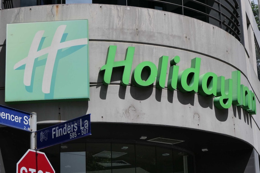 A 'Holiday Inn' sign with street signs showing it is on the corner of Spencer St and Flinders La.