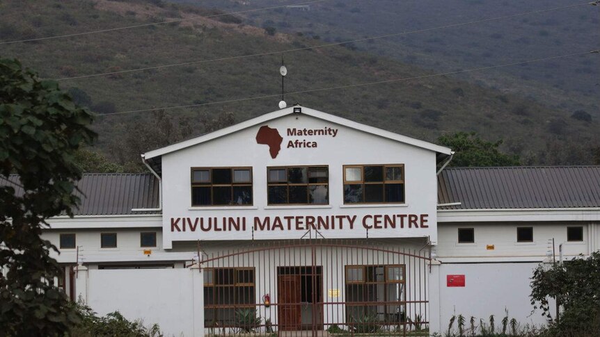A white maternity hospital against a backdrop of hills and scrub.